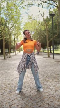 Enerjik dansçı, canlı bir park ortamında müziğin keyfini çıkarıyor.