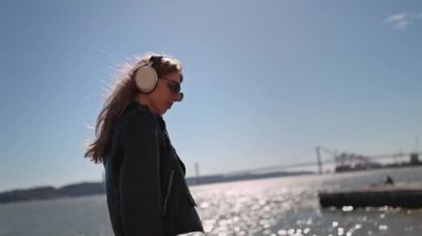 Lizbon, Portekiz 'de Tagus nehrinin yanında müzik dinleyen şık bir kadın.