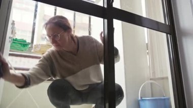 Modern apartmandaki büyük pencereleri temizleyen hizmetçi.