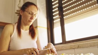 Kızıl saçlı kadın elma ve muzlu meyve salatası hazırlıyor.