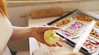 Kadın elmaları pişirmek için hazırlıyor, onları tahta kesme tahtasına kesiyor.