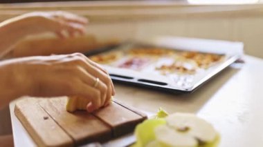 Kadın fırın tepsisinde reçelli böreğe elma dilimleri ekliyor.