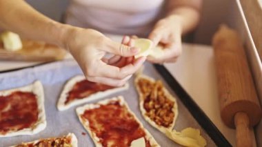 Elmalı turta mini pizza hazırlama, kadın çiğ hamura elma dilimi, domates sosu ve ceviz ekliyor.