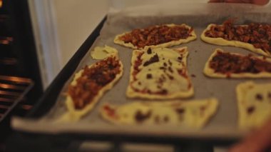 Pişmemiş mini pizzalar pişirmek için sıcak bir fırına konur.