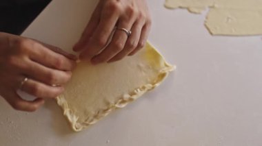 Pasta şefi beyaz masada pişirmek için hamur örüyor.