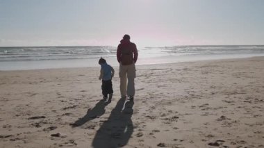 Baba ve oğul kumsalda keyifli bir gezinti yapıyorlar.