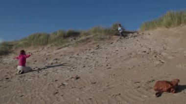 Mutlu anne ve oğul güneşli bir sahilde koşup oynuyorlar.