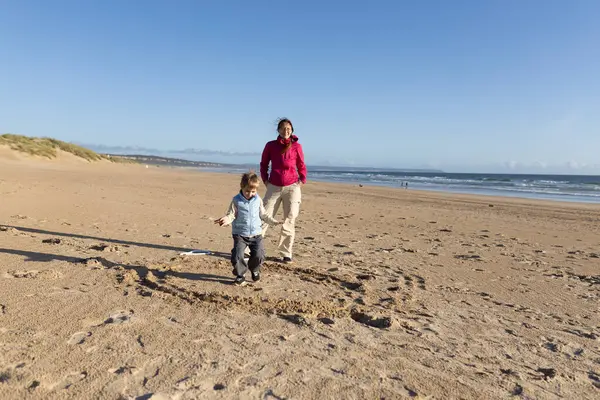 Anne ve oğlu güneşli bir günde sahilde birlikte oynuyorlar.