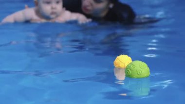 Yüzme dersi sırasında havuzda bebeğe yardımcı olacak nitelikli bir eğitmen.