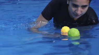 Bebek yüzme kursunda bir bebeğe yardımcı olacak nitelikli bir eğitmen.