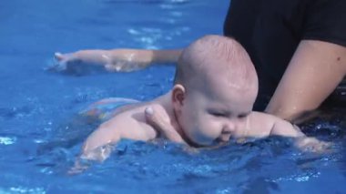 Sevimli bebek havuz hocasıyla yüzmeyi öğreniyor.