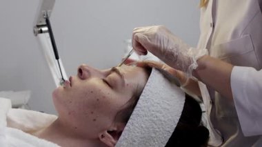 Profesyonel güzellik uzmanı cilt tedavisi için genç kadınların yüzüne kimyasal kabuk takıyor.