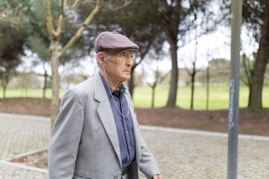 Huzurlu bir park ortamında rahatlatıcı bir yürüyüş sırasında müziğin tadını çıkaran kıdemli bir adam.