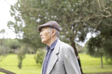 Huzurlu bir parkta rahatlatıcı bir yürüyüş sırasında kulaklık takan son sınıf öğrencisi müziğin keyfini çıkarıyor.