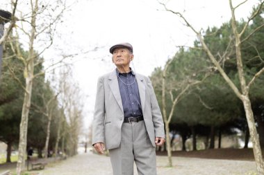 Şık bir kıdemli adam ağaçlarla kaplı bir park yolunda rahatça geziniyor.