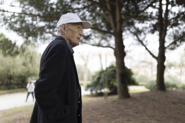 Huzurlu bir parkta rahatlatıcı bir yürüyüş sırasında müziğin tadını çıkaran kıdemli bir adam.