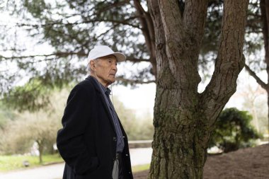 Huzurlu bir park ortamında müzik dinleyen, rahatlık ve sükuneti kucaklayan kulaklık takan kıdemli bir adam.