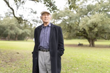 Kıdemli Asyalı adam sakin bir park ortamında sakin bir günün tadını çıkarıyor.