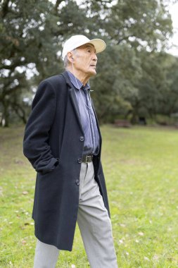 Yaşlı profesör parkta yürürken müzikle eğleniyor, boş zamanı akademik hayatla birleştiriyor.