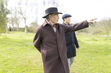 Yaşlı adam parkta yürürken oğluna bir şey gösteriyor.