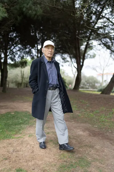 Huzurlu bir parkta sakin bir gezintinin tadını çıkaran kıdemli adam doğanın sükunetini kucaklıyor.