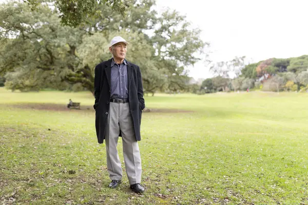 Huzurlu bir parkta durmuş, temiz havanın ve doğanın sükunetinin tadını çıkarıyor.
