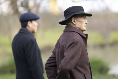 Şapkalı iki son sınıf öğrencisi parkta kameradan uzağa bakıyor.