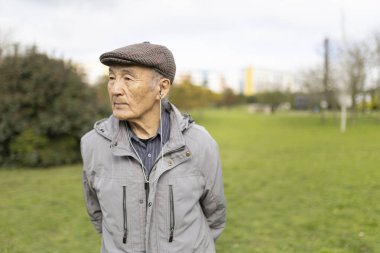 Kulaklık takan ve parkta yürürken müzik dinleyen yaşlı bir adam emekliliğinin tadını çıkarıyor.