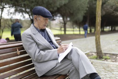 Huzurlu bir park ortamında beste yapan, müzikten hoşlanan ve ilham alan kıdemli yazar.