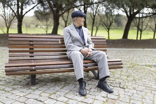 Huzurlu bir park ortamında bankta otururken müzik dinleyen kulaklık takan son sınıf öğrencisi.