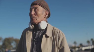 Boynuna kulaklık takan kıdemli Asyalı adam etrafını gözetliyor.