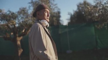 Kulaklık takan son sınıf öğrencisi zeytinlikte müzik dinliyor.