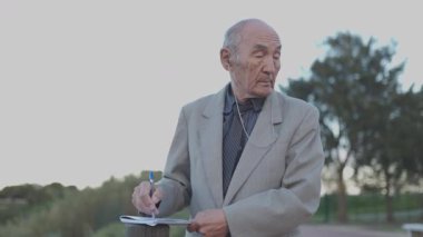 Bir parkta kıdemli gazeteci notlar yazıyor.