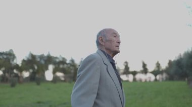 Huzurlu bir parkta rahatlatıcı bir yürüyüş sırasında kıdemli işadamı müziğin keyfini çıkarıyor.