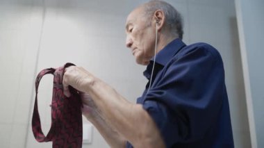 Son sınıf öğrencisi kulaklık takarken kravat takıyor.