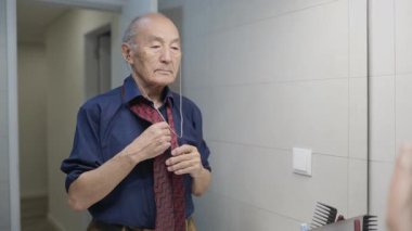 Kıdemli adam banyo aynasında kravatını düzeltiyor, hazırlanıyor.