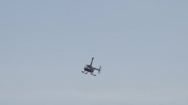 Küçük helikopter açık havada manevra yapıyor.