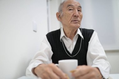 Kulaklık takan son sınıf öğrencisi kahve ve müzikle sessiz bir anın tadını çıkarıyor.