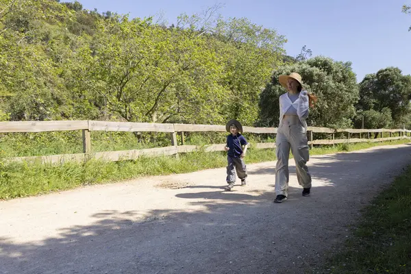 Anne ve oğul, güneşli bir yaz gününde kırsalda keyifli bir yürüyüş yapıyorlar.