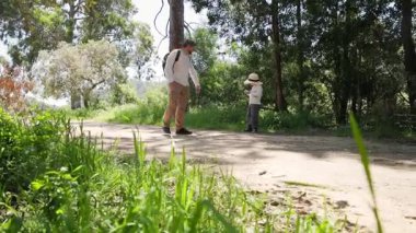 Baba oğul doğa yürüyüşünün tadını çıkarıyorlar, el ele tutuşuyorlar ve konuşuyorlar.