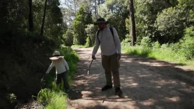 Baba ve oğul güneşli bir günde ormanda yürüyüş yapıyorlar.