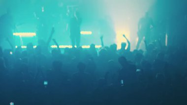 Hayranlar canlı bir müzik konserinden zevk alıyorlar, ellerini sallıyor ve grubu kaydediyorlar.