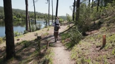 Baba ve çocuk sakin bir orman ortamında gölün kenarında sakin bir yürüyüş yapıyorlar.