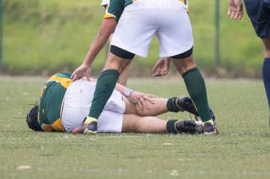 Rugby atletleri, bir müsabaka maçında sahada sakatlanan takım arkadaşına yardım ediyor
