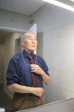 Kıdemli işadamı banyodaki aynada kravatını düzeltiyor, işe hazırlanıyor.