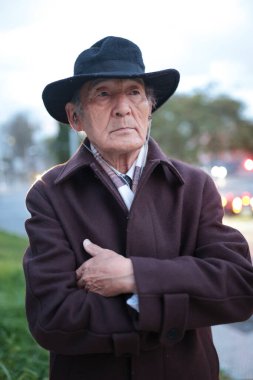 Şapka ve kulaklık takan, kollarını kavuşturmuş şık bir son sınıf öğrencisi.