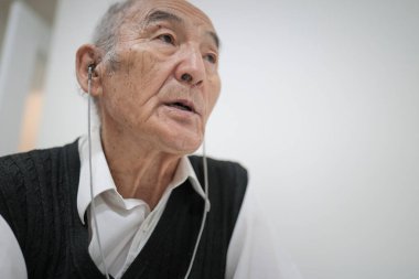 Kulaklık takan yaşlı profesör çevrimiçi konferans veriyor.