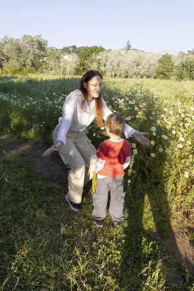 Anne ve oğul papatya tarlasında sıcak bahar güneşinin tadını çıkarıyorlar.