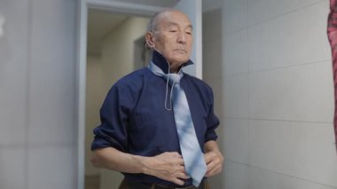 Kıdemli adam sabahları kravatını bağlıyor.