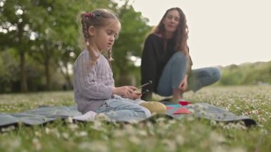 Genç kız annesiyle çayırda davul çalmayı öğreniyor.